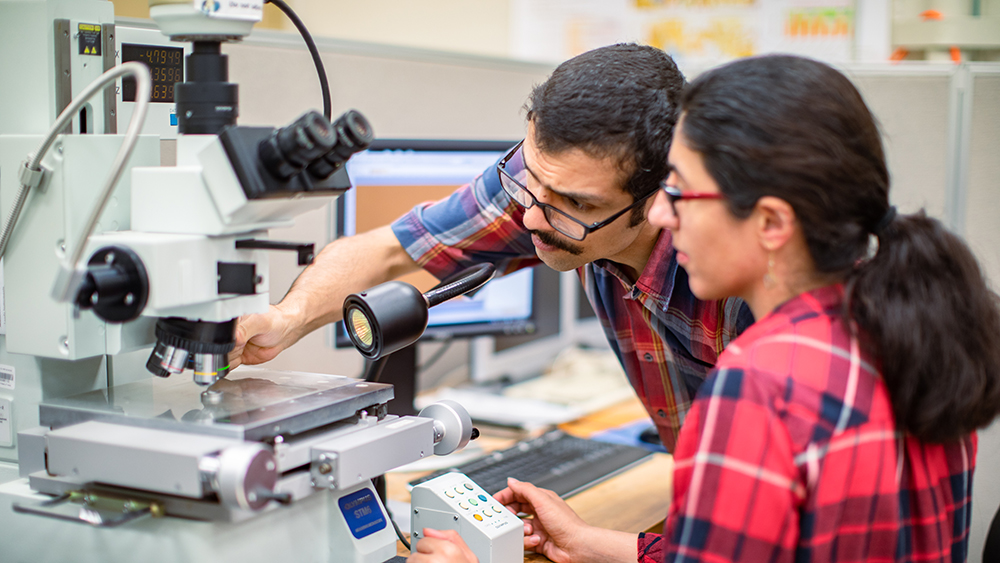 两名学生，一男一女，在计量实验室使用一些技术设备。