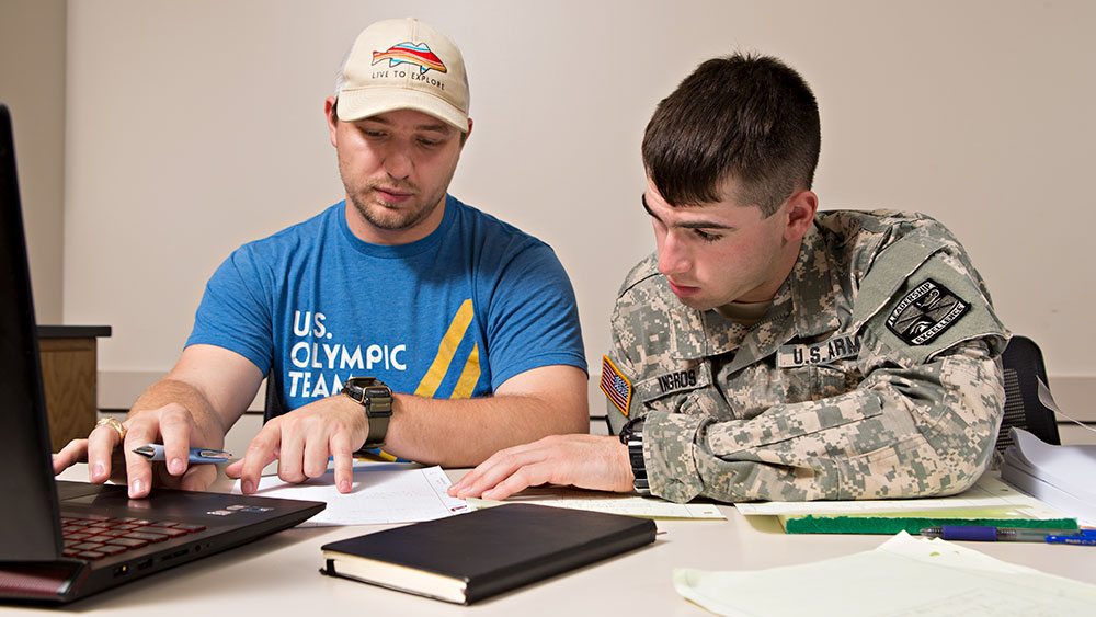 两名男学生，其中一名穿着美军制服在一起学习。