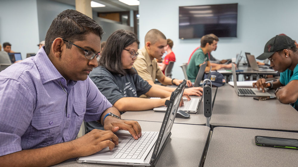 加尔维斯顿德州农工学院的几名男女学生在教室里用笔记本电脑工作。