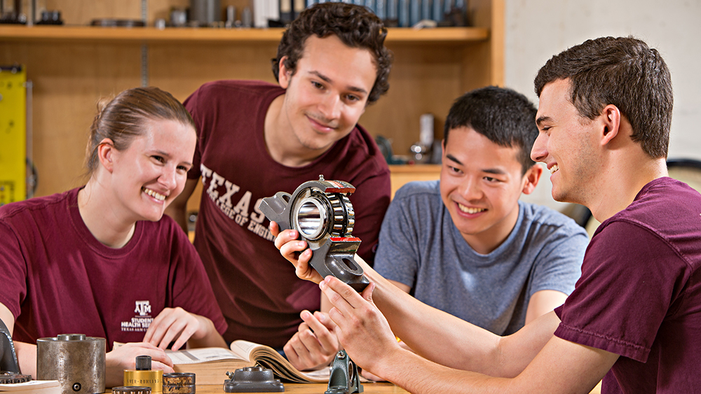 四个微笑的学生看着工程项目