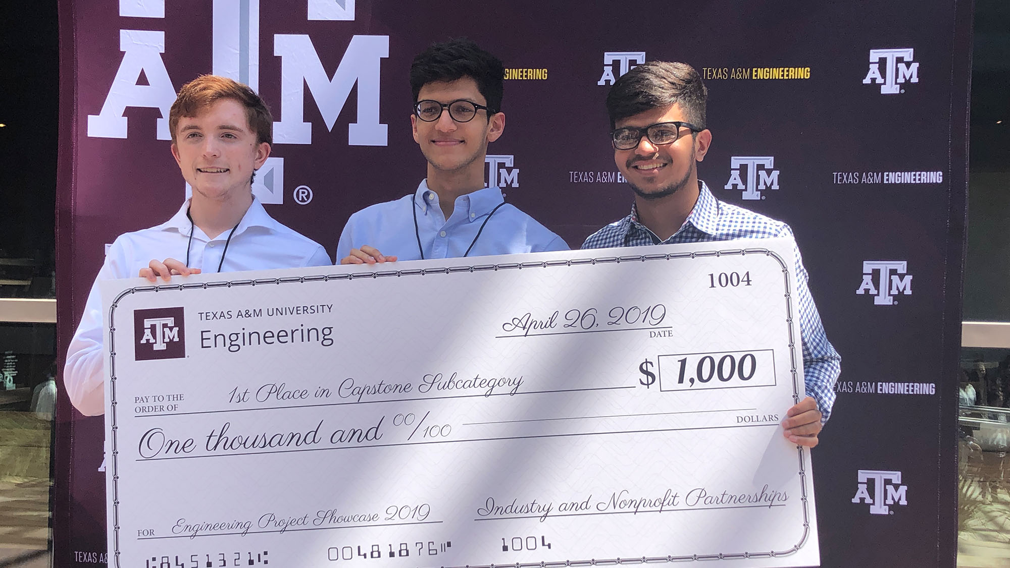 团队成员在获得研究项目的支票后，在德州农工大学的栗色背景前拍照。