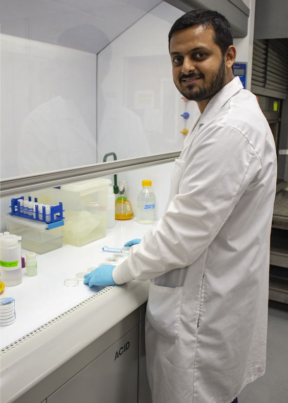 博士生苏拉夫·达斯(Sourav Das)穿着一件白色长外套，在实验室里分析灰尘样本。
