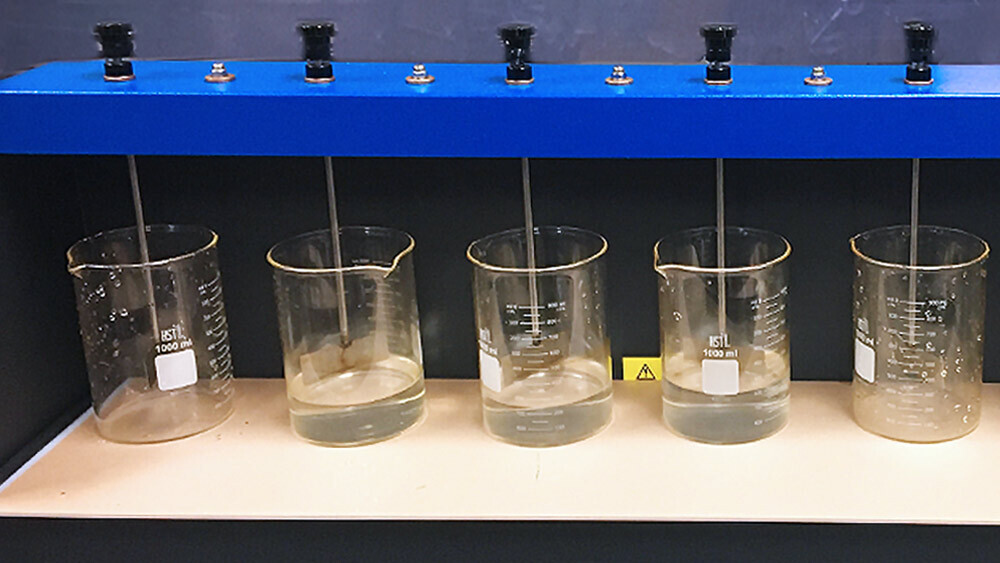一系列透明烧杯，其中一些含有液体，在机器上排列