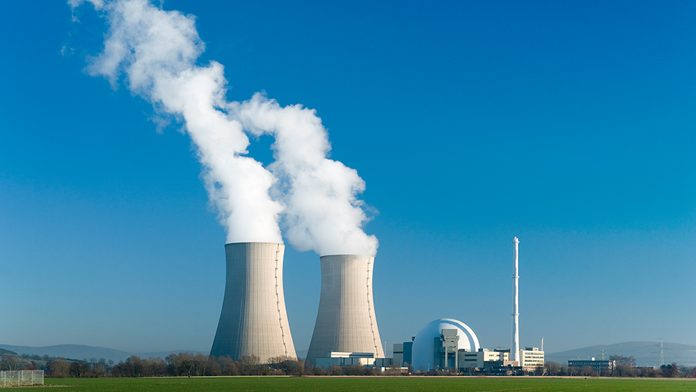 两座核反应堆塔在蓝天的映衬下冒着白烟。
