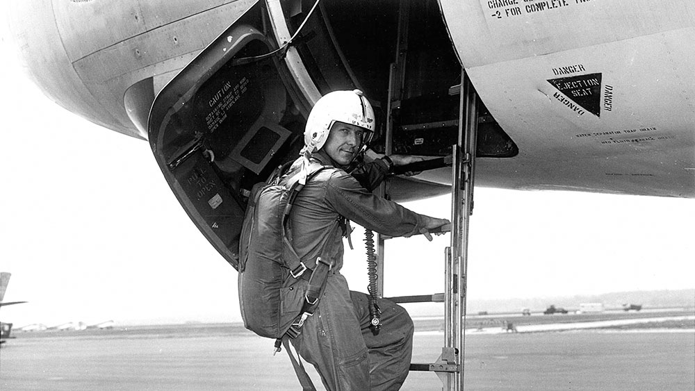 一名男性飞行员登上飞机的黑白照片。