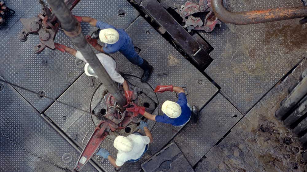 俯视四名戴着安全帽的工人在钻井平台上使用设备