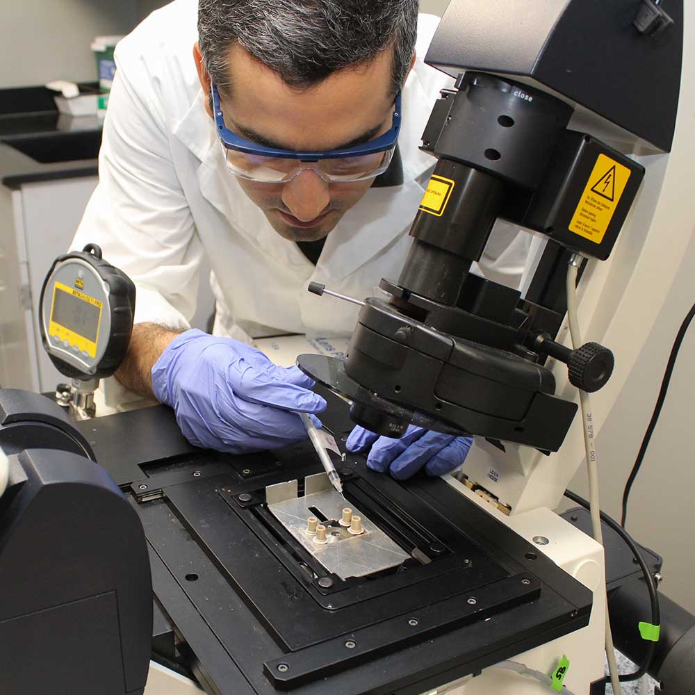 科学家将溶液注入倒置显微镜上的微流体实验中。