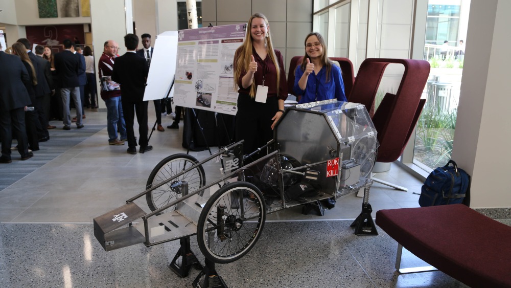 两名学生在2019年工程项目展示会上展示他们的原型。